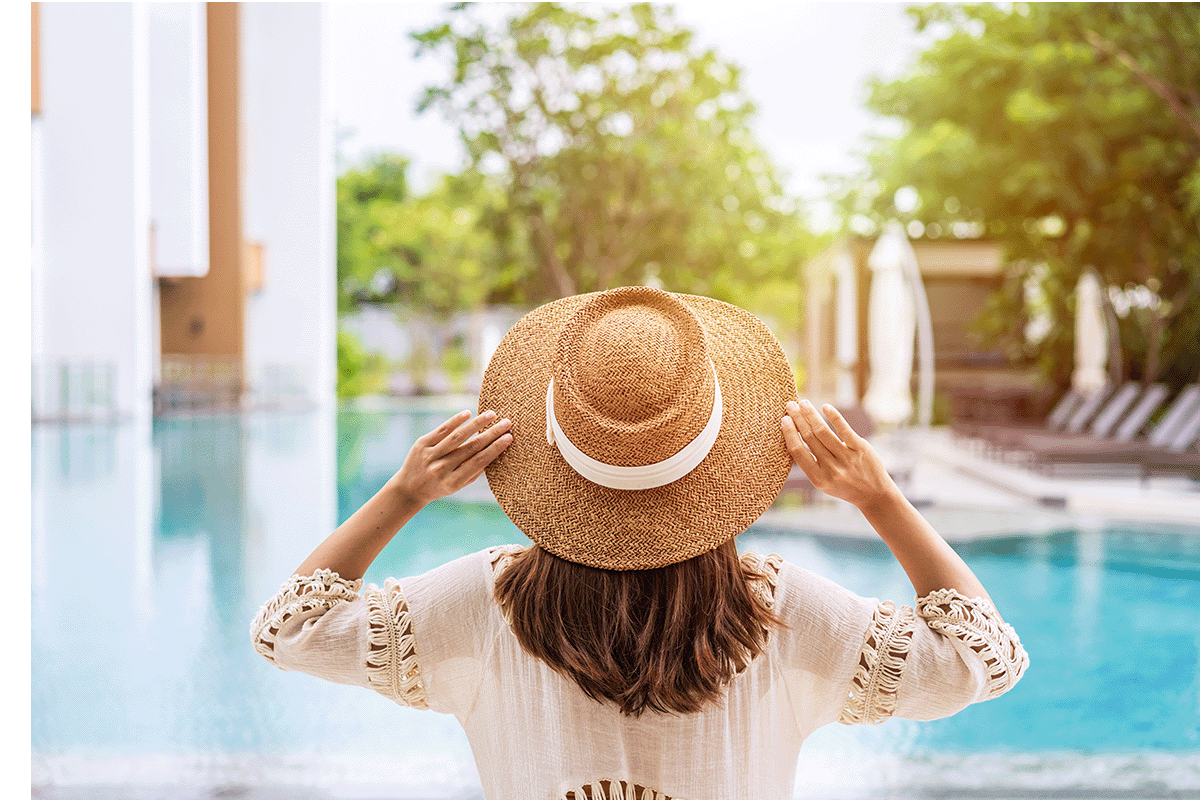 Woman wearing a sunhat standing in front of a pool