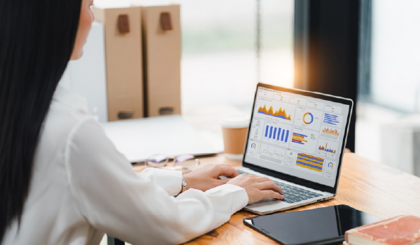 A person looking at a laptop screen with charts and graphs